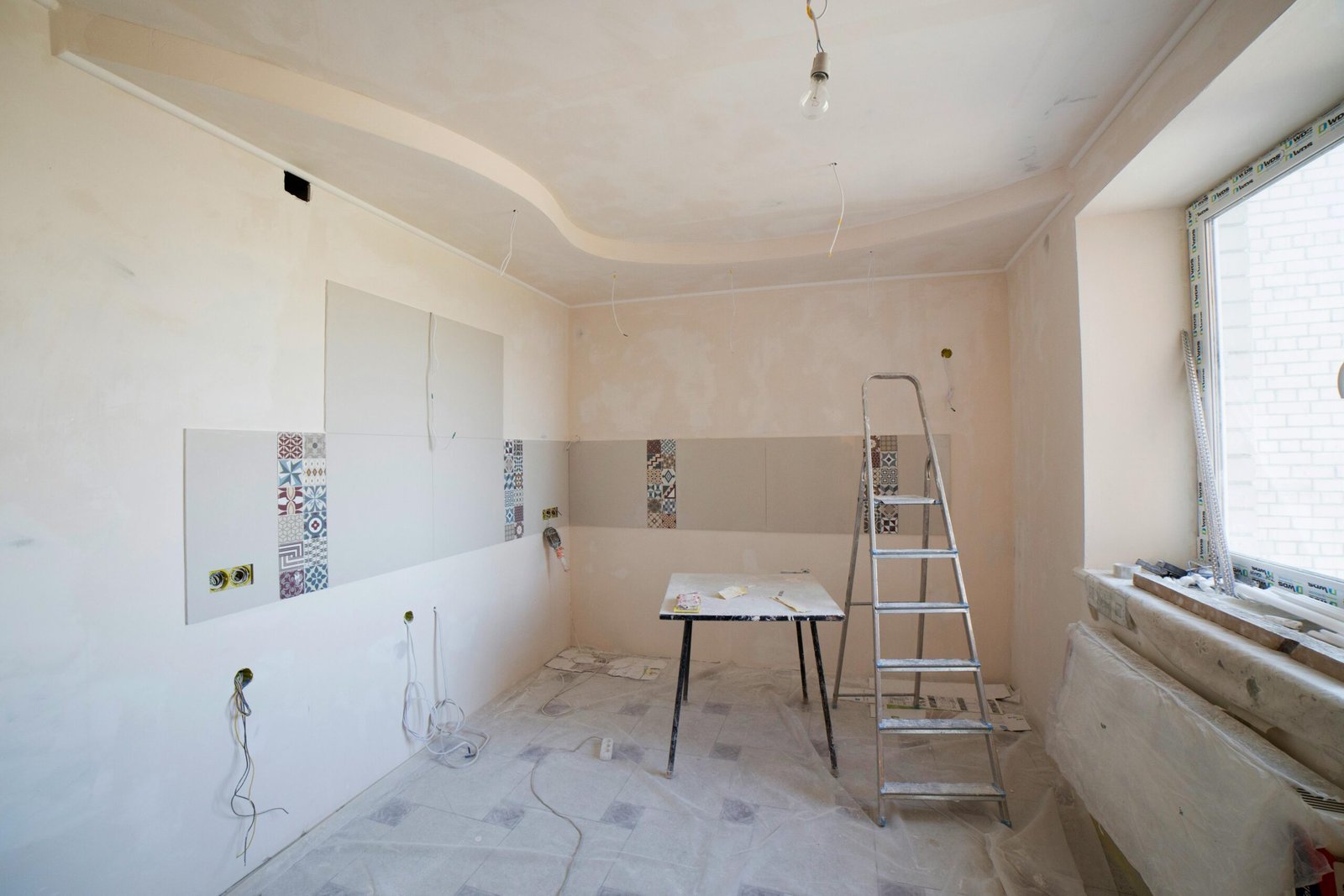 Spacious kitchen under renovation with ladder and tools, showcasing a fresh new design.